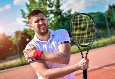 man holding shoulder in pain due to rotator cuff tear from playing tennis
